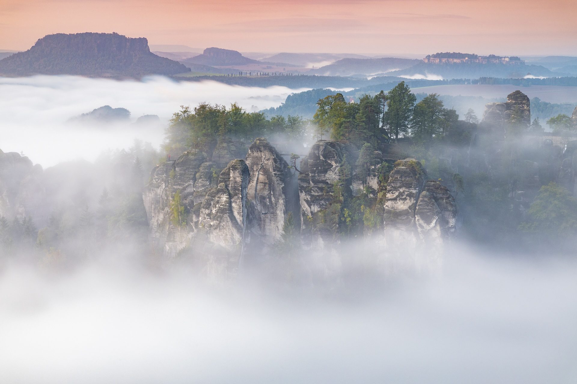 Bastei in der Sächsischen Schweiz: Sandsteinfelsen im Morgennebel, dahinter Lilienstein und Festung Königstein